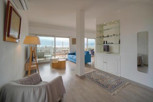 un salon avec un canapé bleu et une chambre avec une fenêtre dans l'établissement Le Val - Rooftop - Parking - VCA, à Cannes