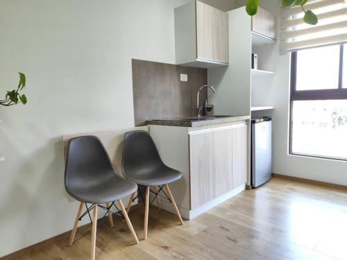 una cocina con 2 sillas frente a un mostrador en Bello monoambiente en pleno prado cochabambino, en Cochabamba