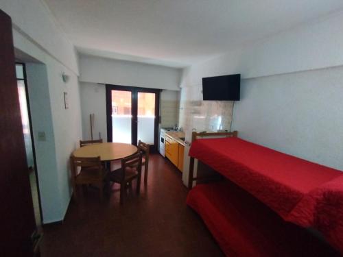 a bedroom with a bed and a table and a kitchen at El Dorado Deptos a una cuadra del mar in San Bernardo