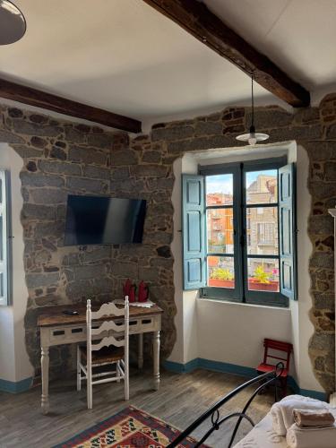 a room with a table and a tv on a brick wall at B&B su Ponte in Orgosolo