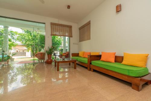 a living room with a green couch and orange pillows at The Calm Of8 in Unawatuna
