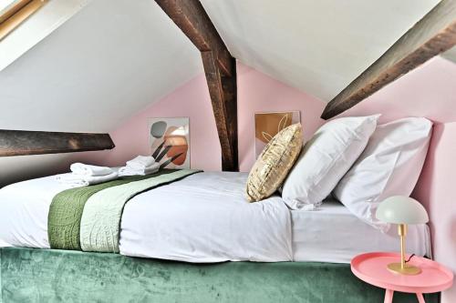 - une chambre avec un grand lit blanc et un mur rose dans l'établissement Loft Mezzanine central à Paris 14ème- II, à Paris