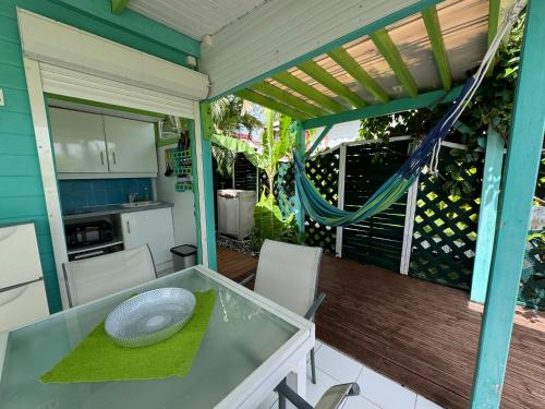 a patio with a table and a kitchen on a deck at Alpinia bungalow in Sainte-Anne