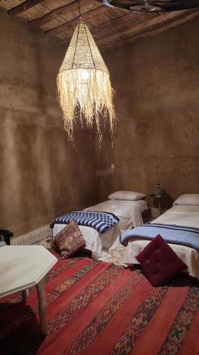 a room with two beds and a chandelier at berber desert home for rent in Merzouga