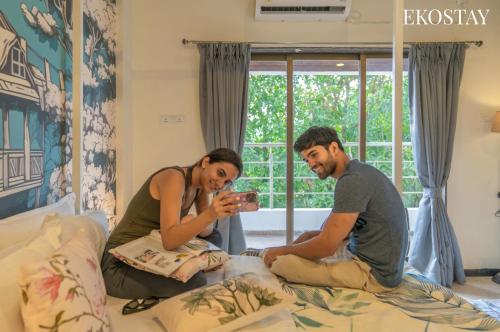 a man and a woman sitting on a bed at EKOSTAY - Amanta Green 8BHK in Karjat