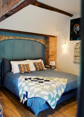 a bedroom with a bed with a blue headboard at The Hornbill at Home Farm Shropshire in Shrewsbury