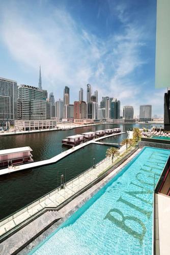 a large swimming pool with a city in the background at Lux Apartment with huge private Lounge I Burj & Canal View in Dubai
