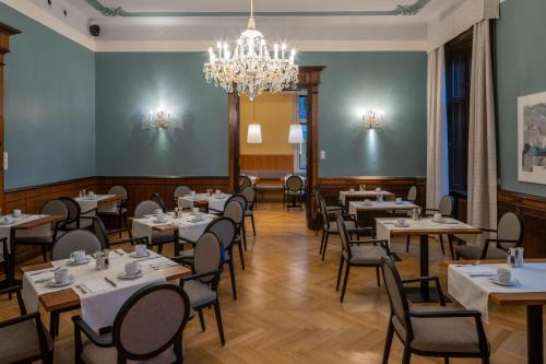 uma sala de jantar com mesas e cadeiras e um lustre em Villa Seilern Vital Resort em Bad Ischl
