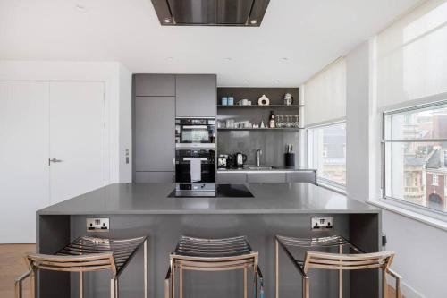 a kitchen with a counter with stools and a microwave at Perfect One Bed in Green Park Station in London