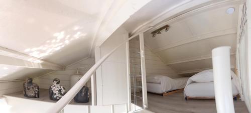 a attic bedroom with two beds and a mirror at Artistiek Vakantiehuisje in Hulst