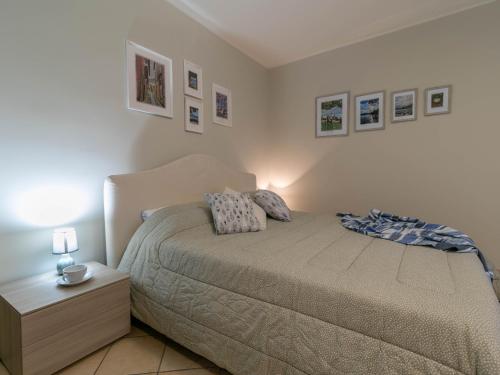 a bedroom with a bed and a nightstand and pictures on the wall at A Due Passi dal Lago Welcomely in Tremezzo