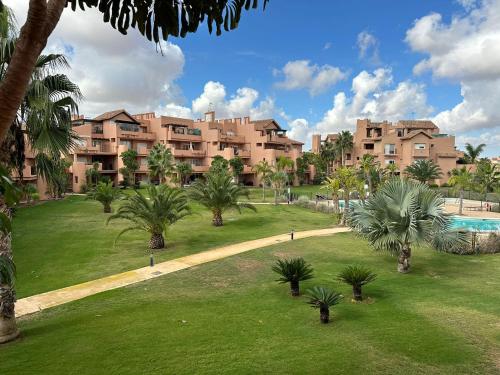 a large apartment complex with palm trees and a swimming pool at Mar Menor Golf Resort 2 Bed Apartment in Los Martínez
