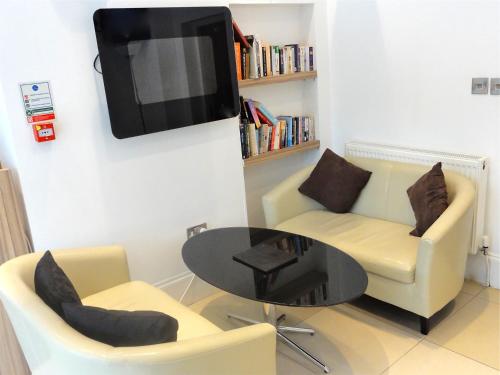 a living room with a table and two chairs and a tv at Skylark Guest House in Hounslow