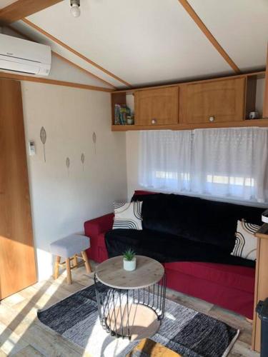 un salon avec un canapé rouge et une table dans l'établissement Mobile home camping calm, à Saint-Pée-sur-Nivelle