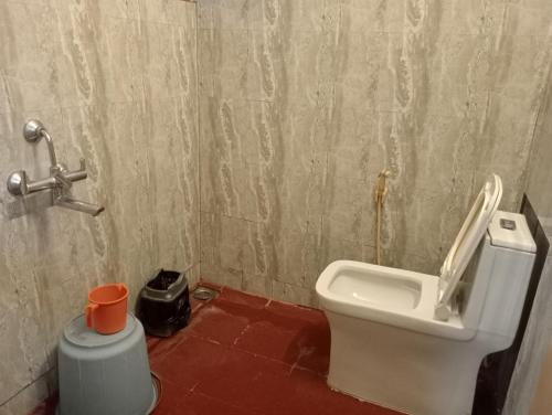 a bathroom with a toilet and a trash can at Hotel Hill Town Coorg in Madikeri