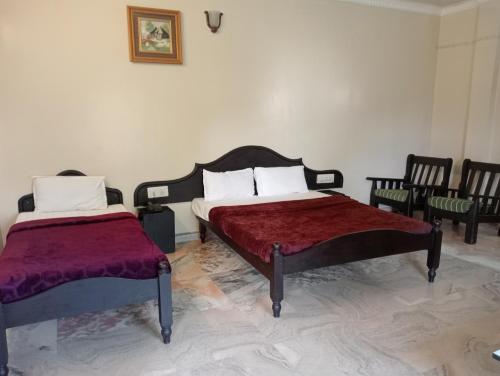 a bedroom with two beds and chairs in it at Hotel Hill Town Coorg in Madikeri