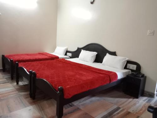 a bedroom with two beds with red sheets and white pillows at Hotel Hill Town Coorg in Madikeri