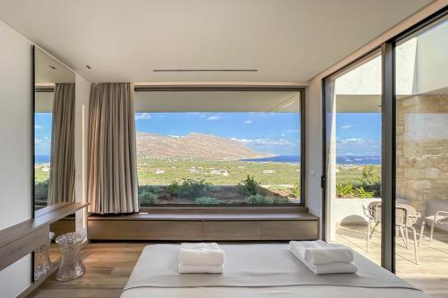 a bedroom with a bed and a large window at Youphoria Sea View Villas in Kissamos