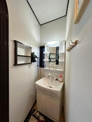 ein weißes Badezimmer mit Waschbecken und Spiegel in der Unterkunft 青砥駅徒步5分 Aoto だるま宿 in Tokio