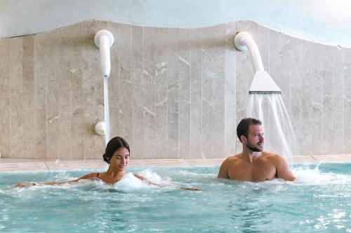 a man and a woman in a swimming pool at Almar Timi Ama Resort & Spa in Villasimius