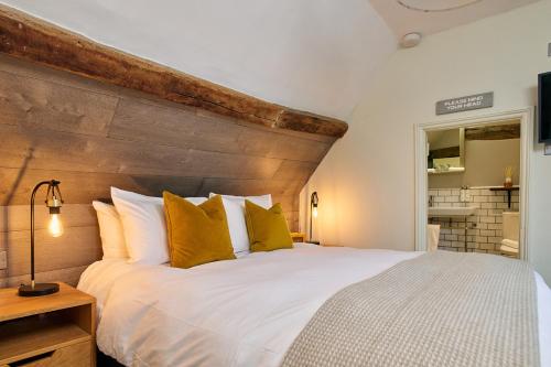 a bedroom with a large white bed with yellow pillows at The Red Lion in Odiham