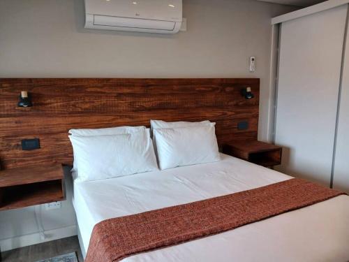 a bedroom with a white bed with a wooden headboard at 101 Mossel Cove in Mossel Bay