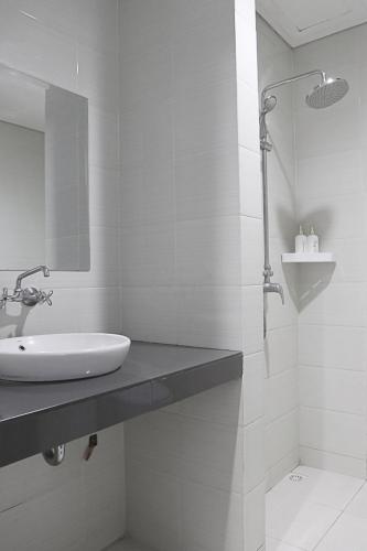 a white bathroom with a sink and a shower at Ronta Bungalows in Legian