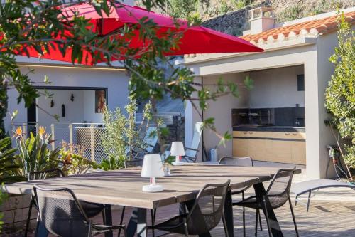 une table en bois avec des chaises et un parapluie rouge dans l'établissement Les Mille et une Vitres - Villa d'architecte, à Port-Vendres