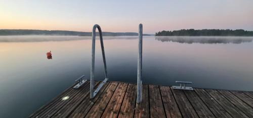 a dock with two sticks in the middle of a lake at Pokój z widokiem na jezioro in Pluski