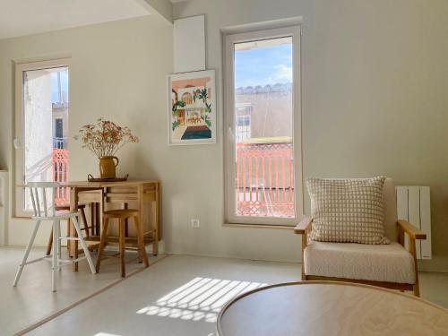 a living room with a table and chairs and a window at Le Joyeux - T3 au coeur du Quartier Haut in Sète