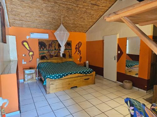 a bedroom with a bed in a room with orange walls at Hotel Club Safari in Mbour