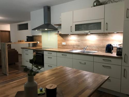 a kitchen with white cabinets and a wooden table at Appartementhaus Angelika in Nittenau