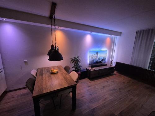 a living room with a wooden table and a television at Mi casa su casa in Schiedam