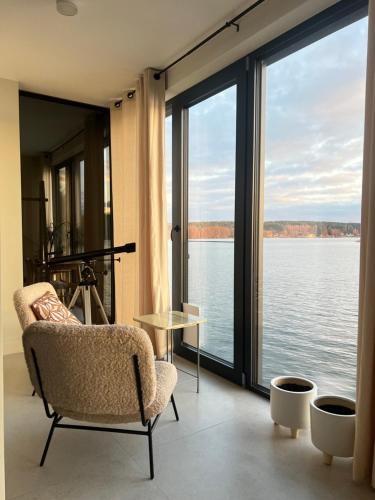 a room with a chair and a view of the water at Pokój z widokiem na jezioro in Pluski