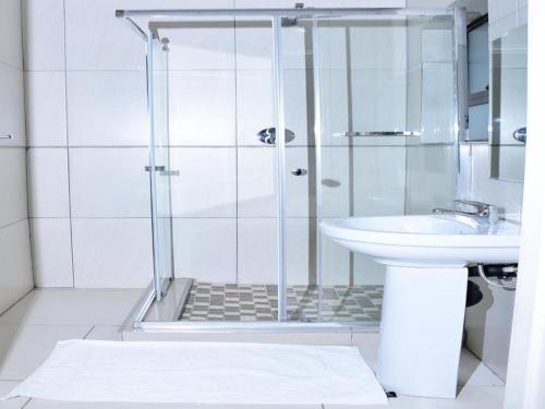 Un baño blanco con ducha y lavabo. en The Guesthouse 8 On Impala, en Polokwane