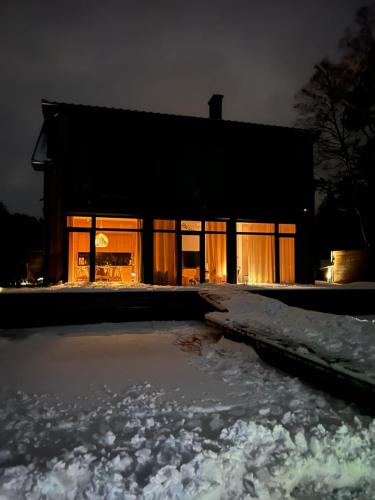 a house lit up at night in the snow at Pokój z widokiem na jezioro in Pluski