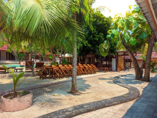 a patio with chairs and tables and palm trees at Jati Village, Party Hostel and Bungalows in Gili Trawangan