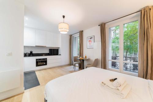 Cet appartement comprend une chambre avec un lit blanc et une cuisine. dans l'établissement Studio refait a neuf montmartre - paris 18 - 2P - FLAT-GUEST, à Paris