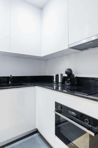 une cuisine avec des armoires blanches et un four à plaques de cuisson dans l'établissement Studio refait a neuf montmartre - paris 18 - 2P - FLAT-GUEST, à Paris