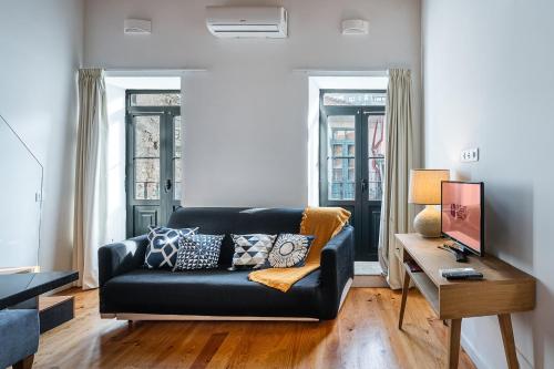 a living room with a black couch and a table at GuestReady - Charming Mezzanine near Porto in Bandeira