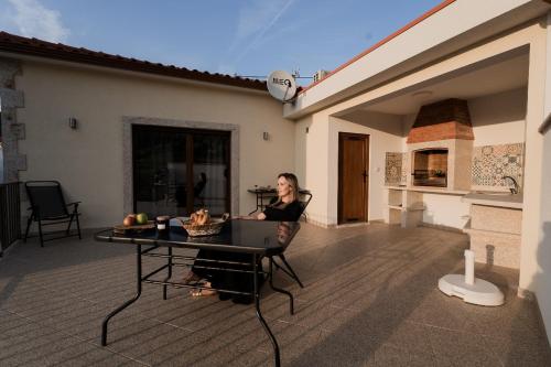 a woman sitting in a chair on a patio with a laptop at Uva Douro Houses in Casais do Douro