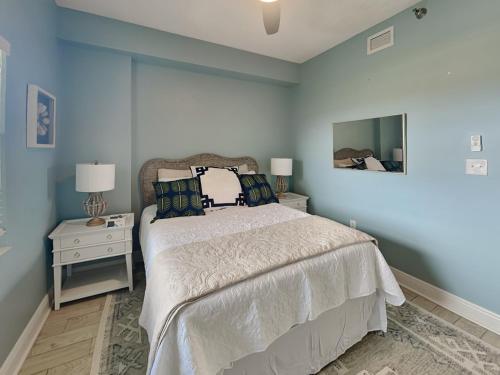 a blue bedroom with a bed and a mirror at Surfview 2408 in Palm Coast