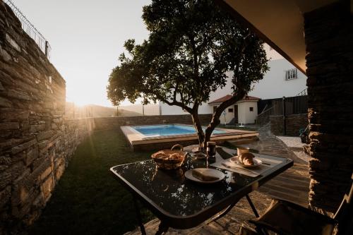 a table with a tree next to a pool at Uva Douro Houses in Casais do Douro