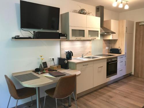 a kitchen with a table and a tv on the wall at Appartementhaus Angelika in Nittenau