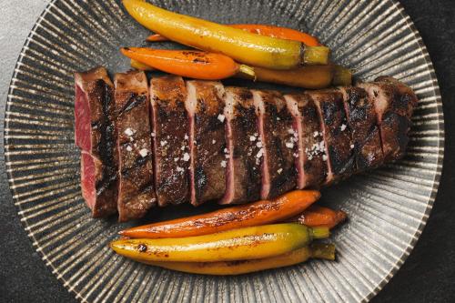 a plate with meat and vegetables on a table at Trobbu Boutique Collection Tulum - All inclusive in Tulum