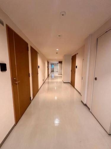an empty hallway of a building with white floors and doors at 503好立地で札幌駅徒歩7分と大通駅徒歩6分で都心を満喫でき綺麗な部屋で快適が生活が実現 in Sapporo