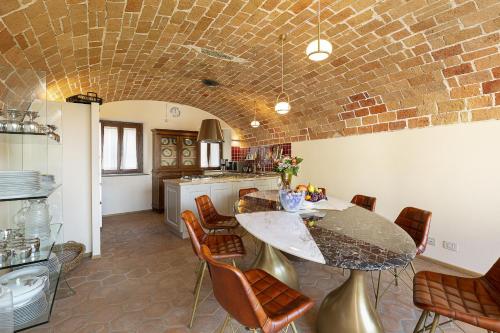a kitchen with a table and chairs and a brick wall at Villa Teresa - Enticing villa with pool and views! in Gabiano