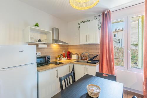 une cuisine avec une table et un réfrigérateur blanc dans l'établissement T3 Aqui es Besièrs - Centre-Historique - Cathédrale & Halles - Clim - Wifi - Free parking sur demande, à Béziers