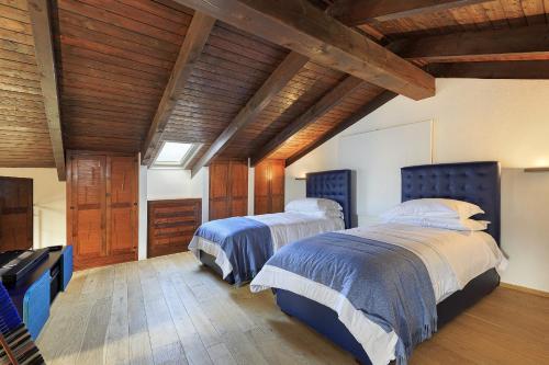 two beds in a bedroom with wooden ceilings at Villa Teresa - Enticing villa with pool and views! in Gabiano