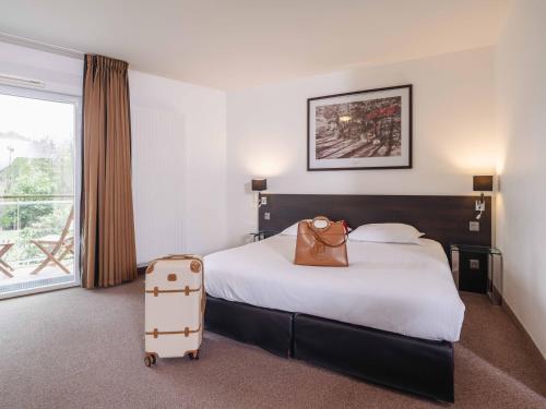 a hotel room with a bed and a suitcase at Westotel Life Nantes Carquefou in Carquefou